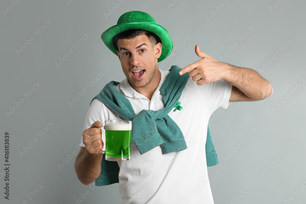 Emotional man in St Patrick's Day outfit with beer on light grey background Emotional man in St Patrick's Day outfit with beer on light grey background