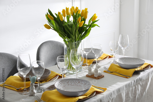 Beautiful Easter table setting with yellow tulips indoors