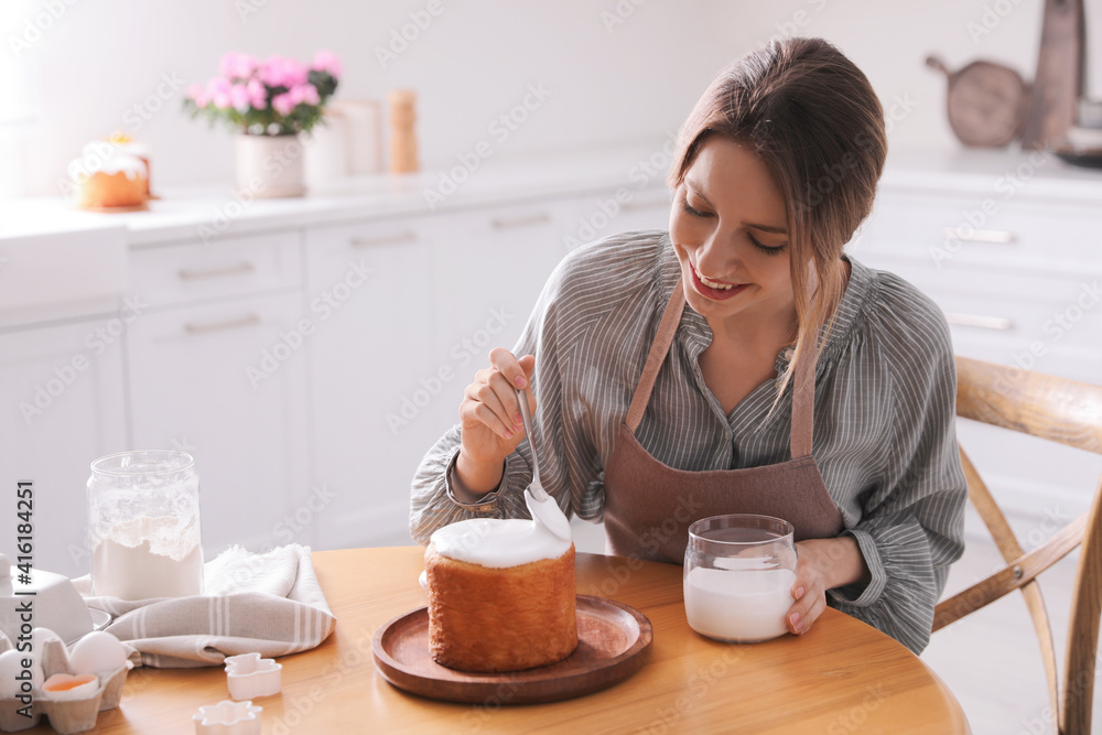 Young woman decorating traditional Easter cake with glaze in kitchen. Space for text Young woman decorating traditional Easter cake with glaze in kitchen. Space for text