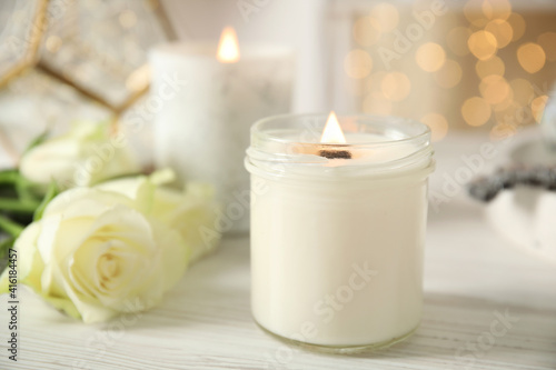 Burning candles in holders on white table