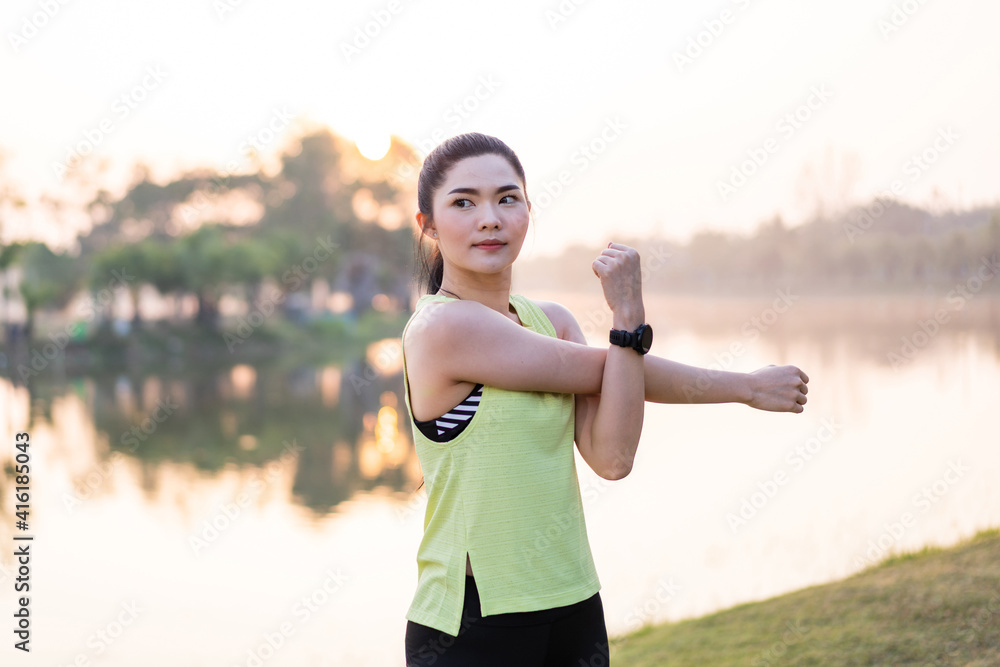 Young beautiful Asian woman in sports outfits doing stretching before workout outdoor in the park in the morning to get a healthy lifestyle. Healthy young woman warming up outdoors. Young beautiful Asian woman in sports outfits doing stretching before workout outdoor in the park in the morning to get a healthy lifestyle. Healthy young woman warming up outdoors.