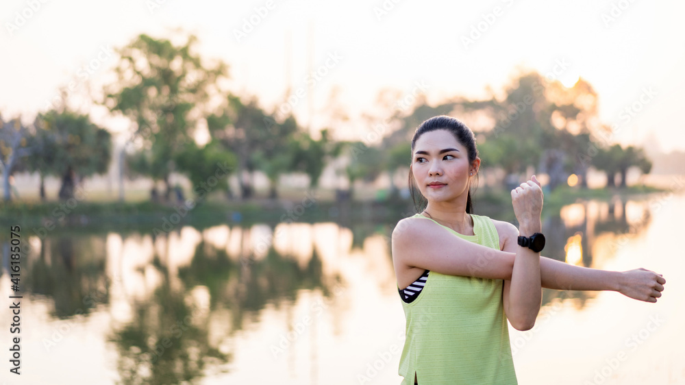 Young beautiful Asian woman in sports outfits doing stretching before workout outdoor in the park in the morning to get a healthy lifestyle. Healthy young woman warming up outdoors. Young beautiful Asian woman in sports outfits doing stretching before workout outdoor in the park in the morning to get a healthy lifestyle. Healthy young woman warming up outdoors.