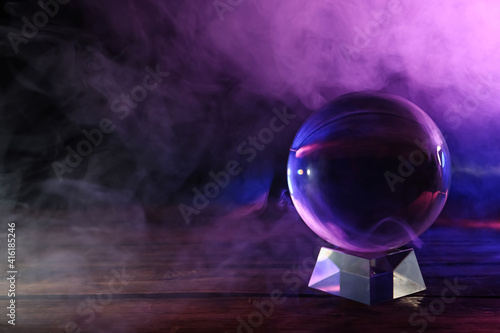 Crystal ball on table and smoke against dark background, space for text. Predictions of future photo