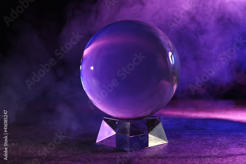 Canvastavla Crystal ball on table and smoke against dark background