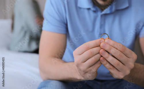 Man with wedding ring in bedroom, closeup. Couple on verge of divorce
