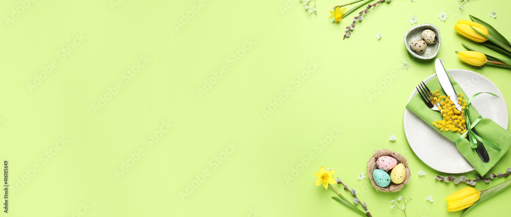 Fototapeta premium Festive Easter table setting with eggs and floral decor on green background, flat lay. Space for text