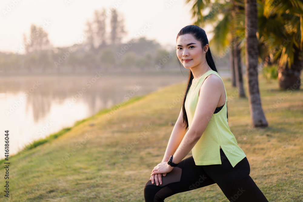 A young Asian female workout before a fitness training session at the park under sunlight in the morning. Healthy young woman warming up outdoors. Sport and recreation A young Asian female workout before a fitness training session at the park under sunlight in the morning. Healthy young woman warming up outdoors. Sport and recreation