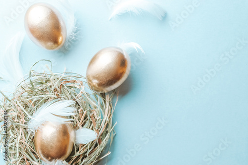 Wallpaper Mural Golden easter colour eggs in basket with white feathers on pastel blue background in Happy Easter decoration. Spring holiday top view concept. Torontodigital.ca