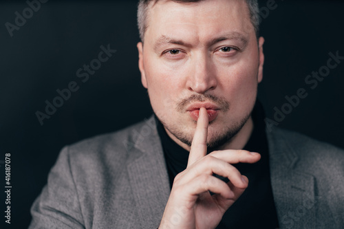 Serious business man showing silence gesture