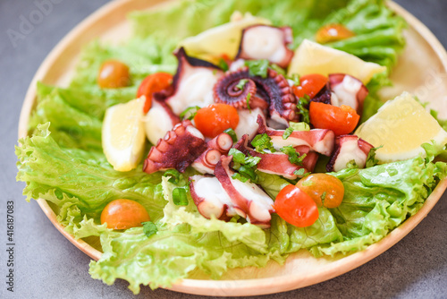 Octopus salad with lemon tomatoes and vegetables on wooden plate Fresh and healthy salad seafood squid and octopus