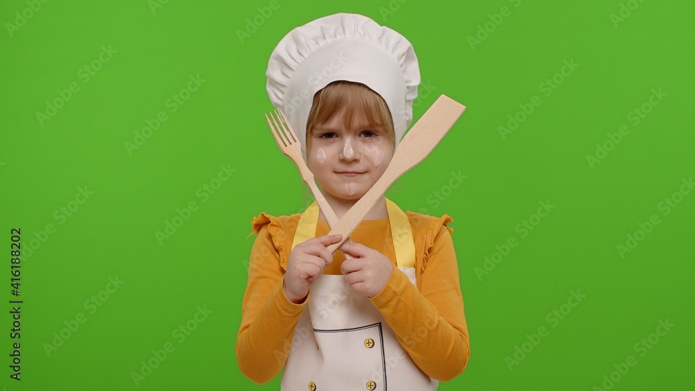 Dissatisfied child girl kid dressed as professional cook chef with wooden fork and spatula, showing symbol of rejection, disagreement on chroma key background. Nutrition, cooking education food school Dissatisfied child girl kid dressed as professional cook chef with wooden fork and spatula, showing symbol of rejection, disagreement on chroma key background. Nutrition, cooking education food school