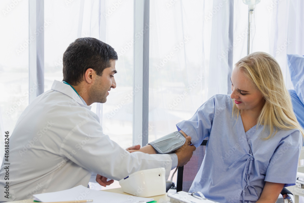 Obraz premium male doctor is putting a cuff of a blood pressure monitor on female patient