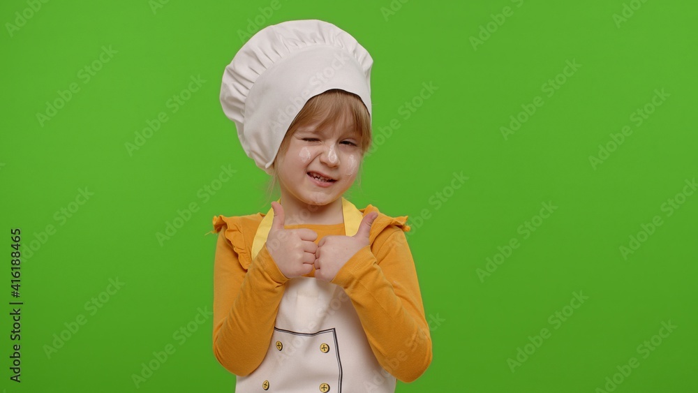 Child girl kid dressed as professional cook chef showing thumbs up, smiling, looking happy at camera on chroma key background. Nutrition, cooking school, education, food. Fun and humor. Copy-space Child girl kid dressed as professional cook chef showing thumbs up, smiling, looking happy at camera on chroma key background. Nutrition, cooking school, education, food. Fun and humor. Copy-space