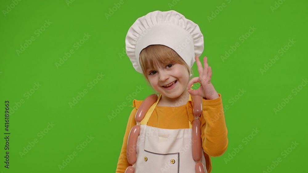 Charming child girl dressed in apron and hat like chef cook showing approval ok sign, invites you to come on chroma key background. Nutrition, family cooking school, children education, restaurant Charming child girl dressed in apron and hat like chef cook showing approval ok sign, invites you to come on chroma key background. Nutrition, family cooking school, children education, restaurant