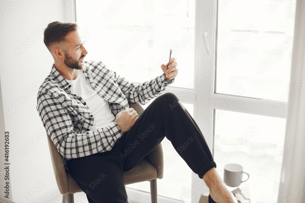 Portrait of mature man relaxing at home. Guy sittng on the chair and use the phone. Portrait of mature man relaxing at home. Guy sittng on the chair and use the phone.