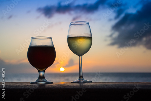 Sunset drinks. A glass of white wine and a glass of dark been are to be enjoyed by the ocean at the end of the day