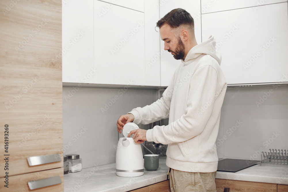 Portrait of mature man relaxin in a kitchen. Guy prepares tea.