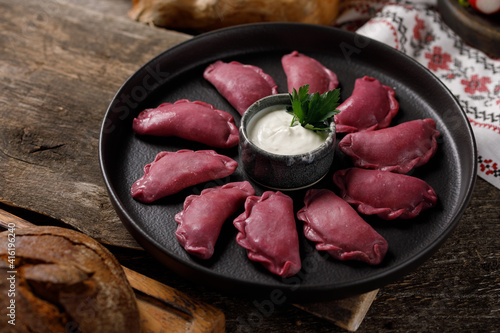 Delicious traditional Russian dumplings, handmade dough painted with beets. Still life on a wooden board. Close-up. photo