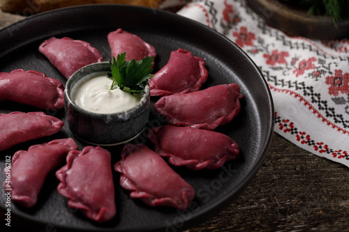 Delicious traditional Russian dumplings, handmade dough painted with beets. Still life on a wooden board. Close-up. photo