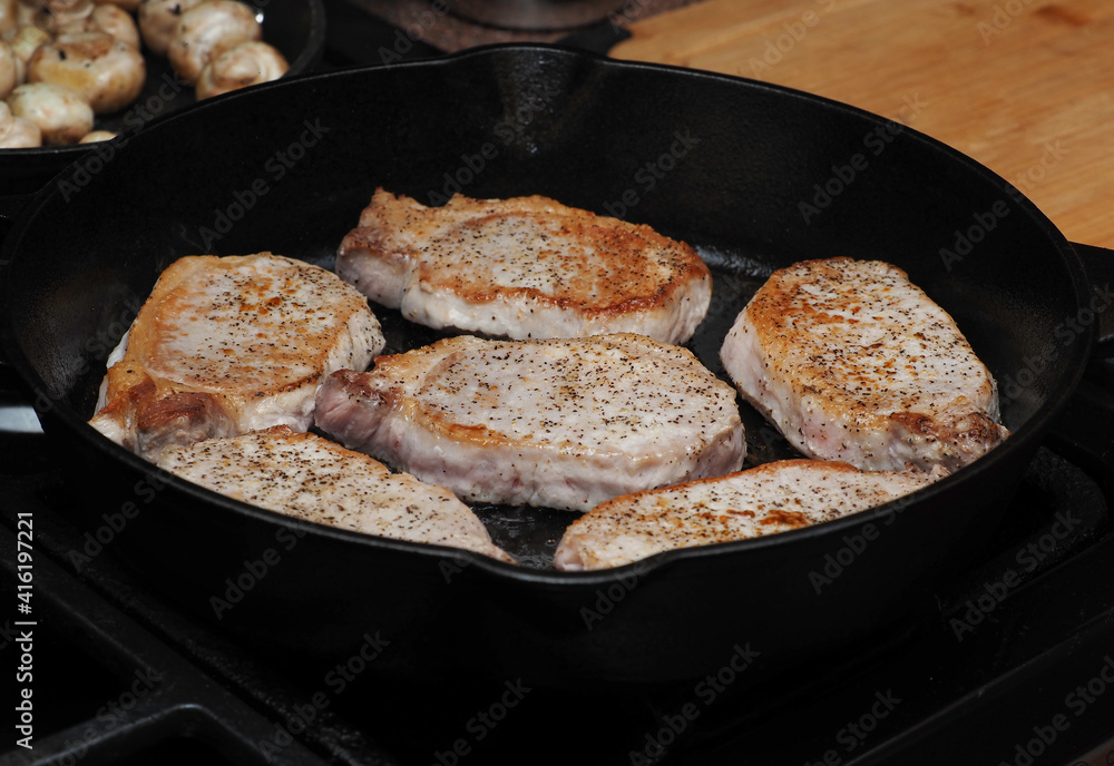 Pork loin Cuts cooking in a cast iron pan Pork loin Cuts cooking in a cast iron pan