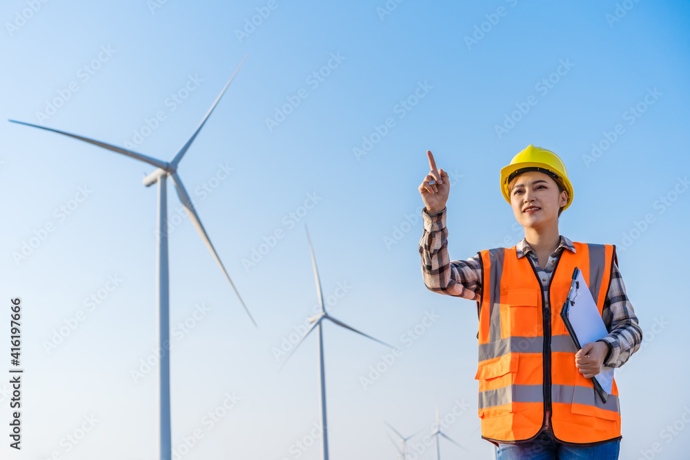 female engineer working against wind turbine farm female engineer working against wind turbine farm