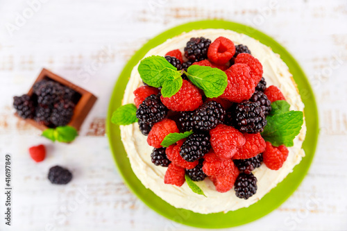 Top view of homemade berry cake decorated with fresh raspberries and blackberries.