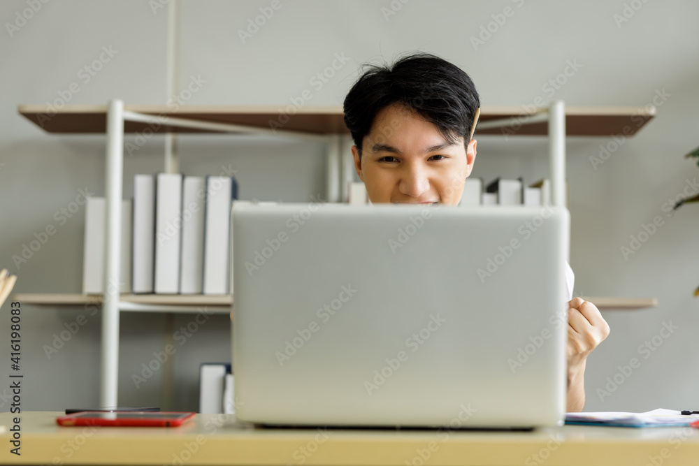 young businessman sitting cheering for football on the laptop young businessman sitting cheering for football on the laptop