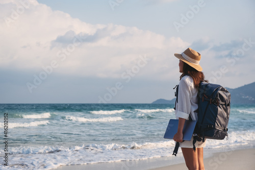 A female traveler holding laptop computer while walking on the beach photo