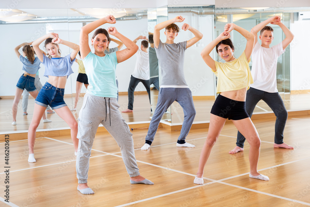 Positive teenage dancers doing dance workout during group class