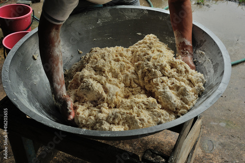 Male hands stir wheat dough on a big pan while making misua, a traditional longevity noodles.  photo