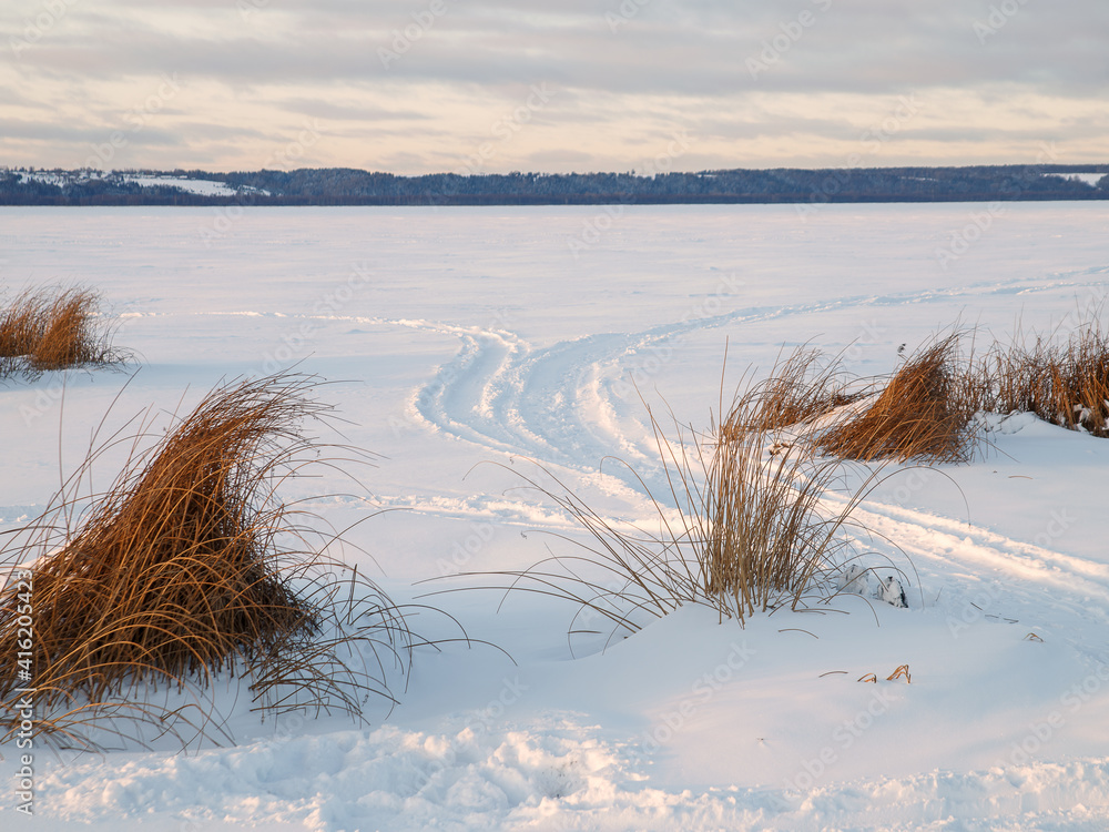 Trail of snowmobile on white snow surface of frozen lake Trail of snowmobile on white snow surface of frozen lake