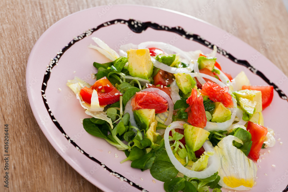 Healthy vegetarian food, salad with avocado, grapefruit, tomatoes, corn salad and sliced onion rings