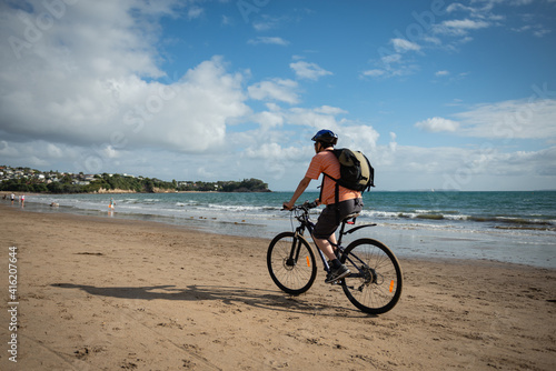Cycling on the Milford beach with out-of-focus people doing their morning walk. © Janice