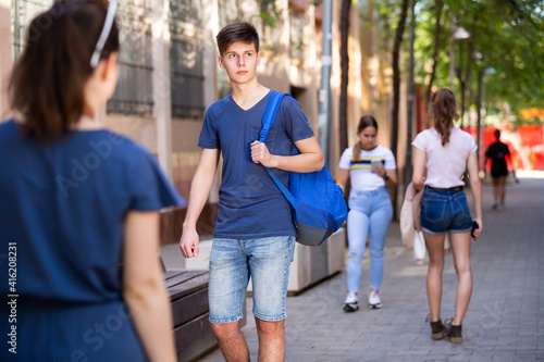 Positive teenager walking in the street, carrying a bag on one shoulder