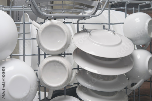 white plates and mugs after cleaning in the automatic dishwasher