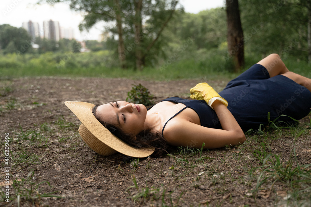 a girl of Asian appearance in a straw hat and yellow gloves lies on the ground in a dress a girl of Asian appearance in a straw hat and yellow gloves lies on the ground in a dress