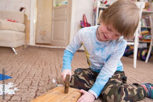 The boy learns to hammer in nails.