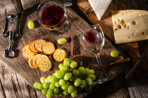 Tasting cheese platter with grapes and fruits on an old wooden table. Food for wine and romantic, cheese delicacies. Menu design horizontally. View from above.