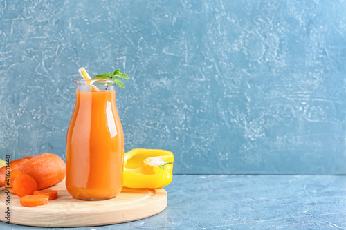 Bottle of healthy smoothie with carrot and bell pepper on color background