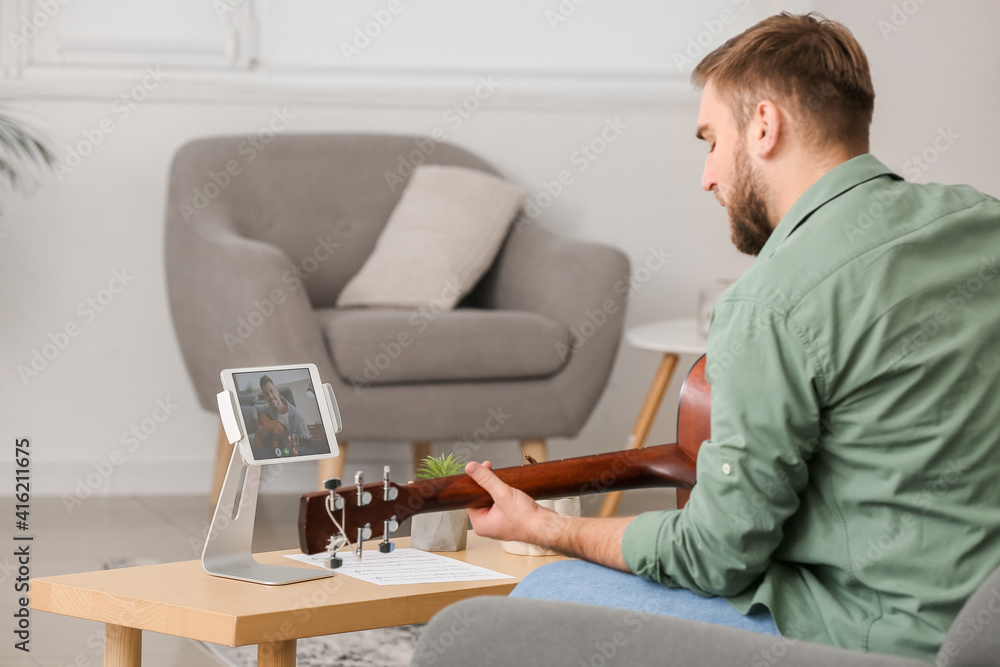 Young man taking music lessons online at home