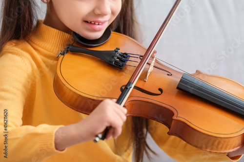 Little girl playing violin at home, closeup