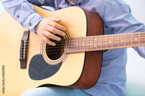 Little boy playing guitar at home, closeup