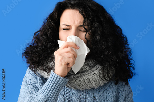 Sick young woman on color b...