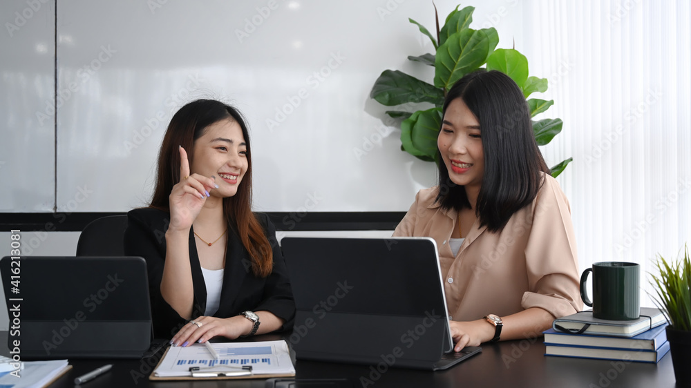 ฺTwo young businesswoman working with computer tablet and discussing project in office. ฺTwo young businesswoman working with computer tablet and discussing project in office.