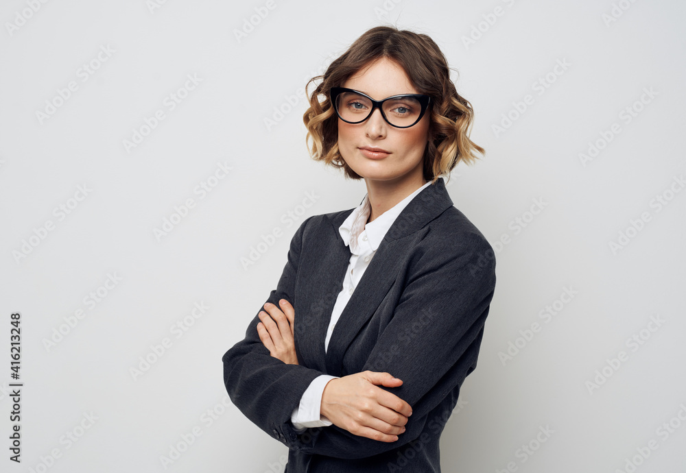 A business woman in glasses and in a suit on a light background crossed her arms over her chest A business woman in glasses and in a suit on a light background crossed her arms over her chest