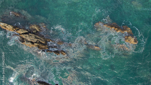 Aerial view of waves swirling around rocks in the ocean