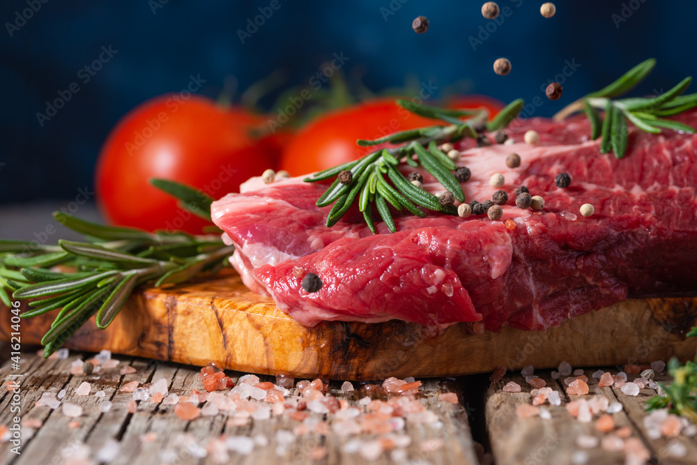 fresh beef steak with rosemary. Vegetables sprinkled with black peppercorns on the background, freeze in motion