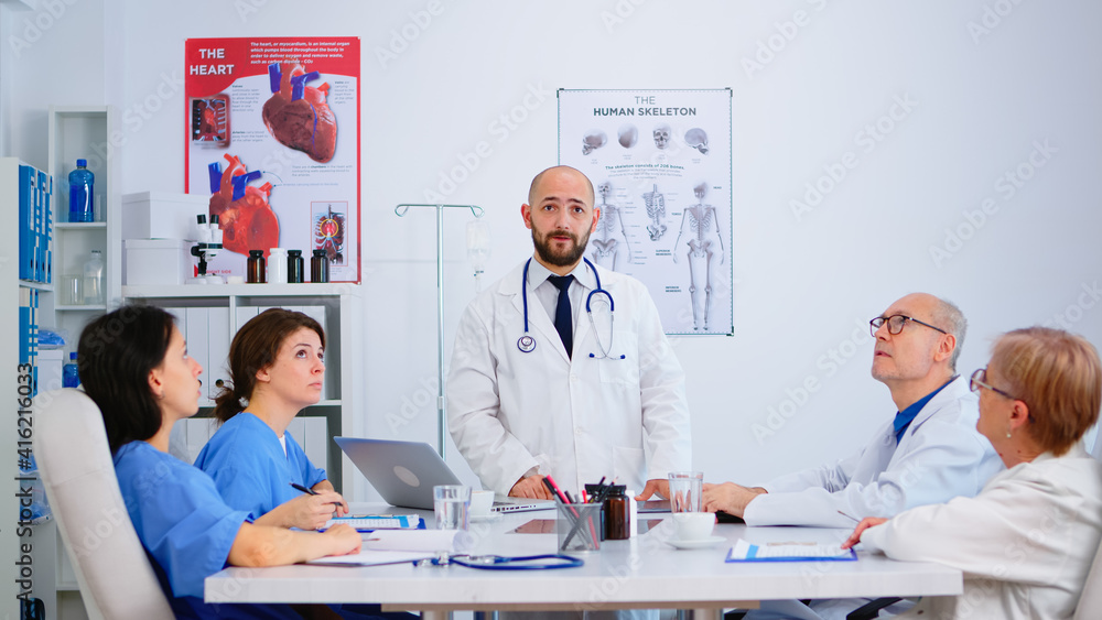 Young specialist doctor explaining diagnosis for patients treatment issues record using virtual reality in workplace. Discussing with medical team during brainstorming, coworkers taking notes. Young specialist doctor explaining diagnosis for patients treatment issues record using virtual reality in workplace. Discussing with medical team during brainstorming, coworkers taking notes.