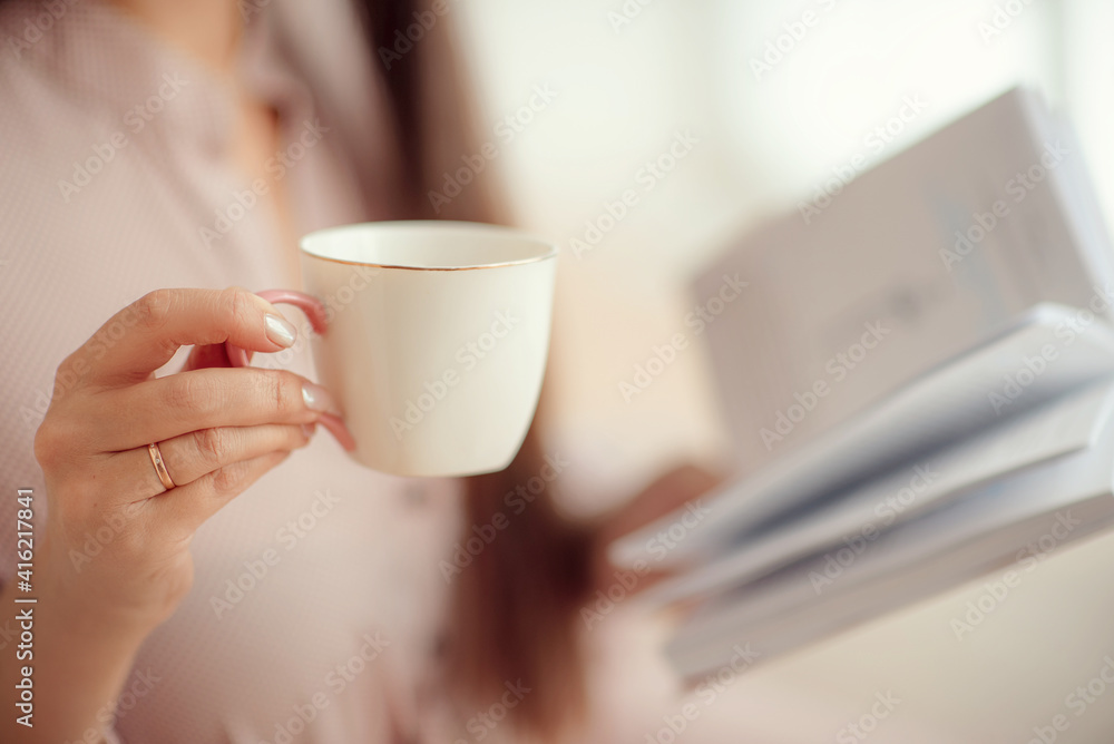 a girl in a pink pink dress holds a white coffee cup and reads a book a girl in a pink pink dress holds a white coffee cup and reads a book