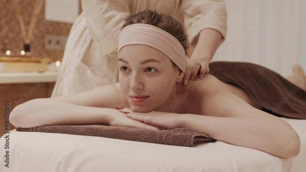 Lockdown of young Caucasian woman lying on massage table in spa center and having relaxing back massage Lockdown of young Caucasian woman lying on massage table in spa center and having relaxing back massage